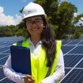 tech - smiling woman in hard hat with clip board and solar panels