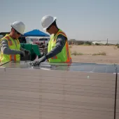 Two people in safety gear preparing to lay out solar panels