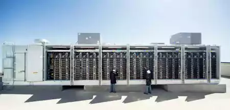 people in front of large solar batteries