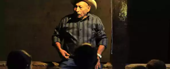 Man talking to a a crowd of children at night.