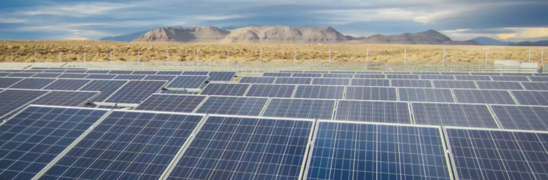 A field of solar panels with mountains in the distance