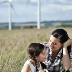 A woman and child together with a field and windmills visible in the distance.