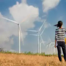 Woman with hardhat looking at wind farm