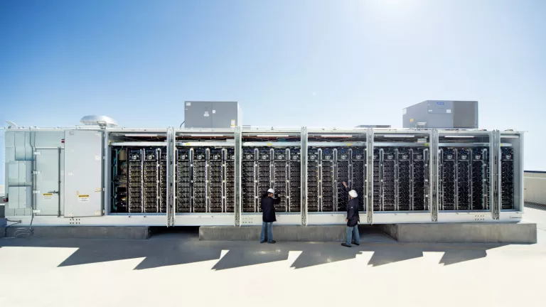 people in front of large solar batteries