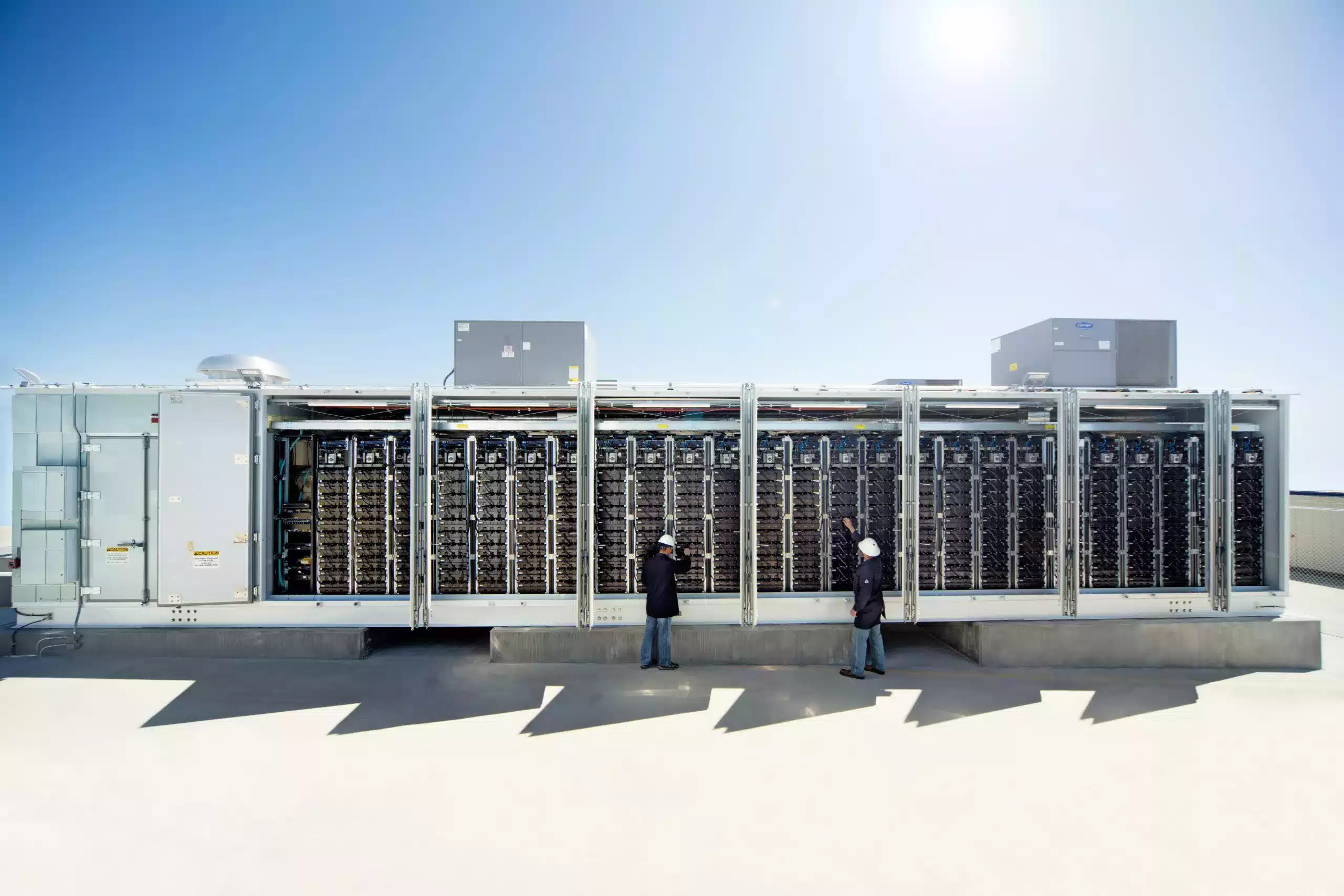 people in front of large solar batteries