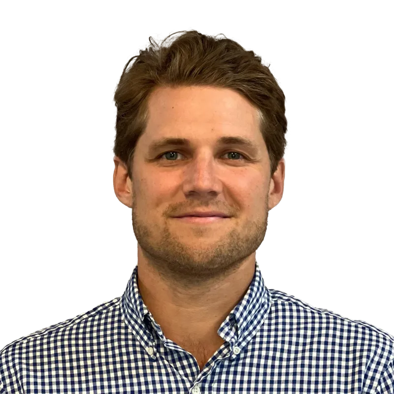A professional headshot of Graham Basecke, wearing a checkered shirt and smiling against a neutral background.