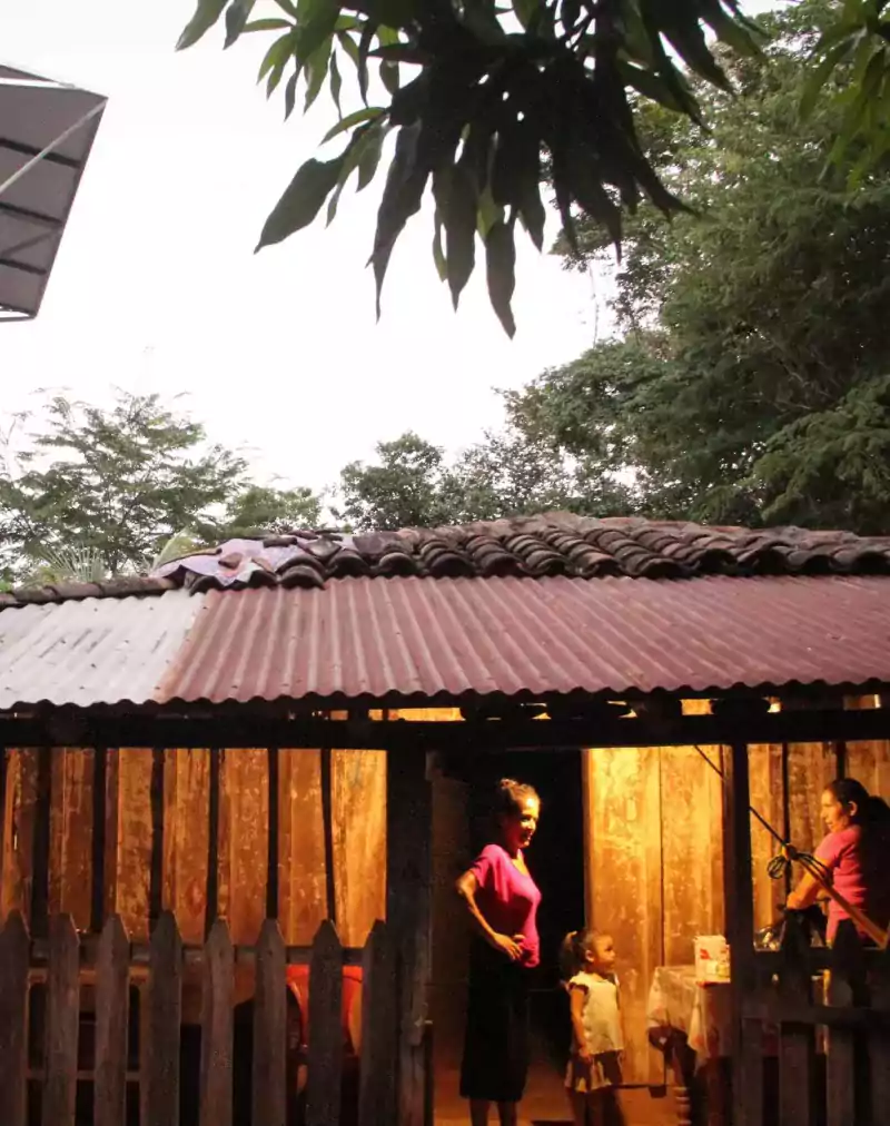 House lit up at dusk with family outside