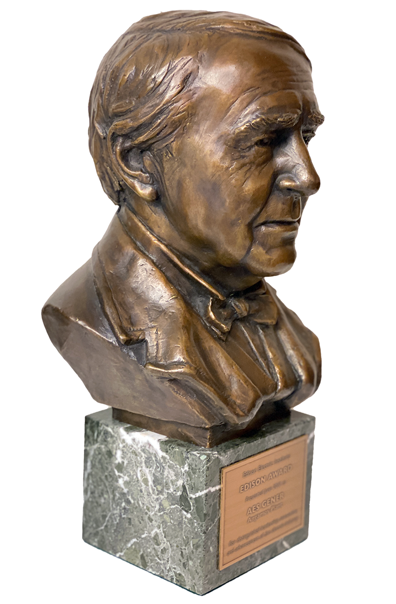 Bronze bust of a man with detailed facial features, mounted on a green marble base with a plaque that reads 'Edison Award.' The sculpture is shown from a side angle, highlighting the man's suit and bow tie.