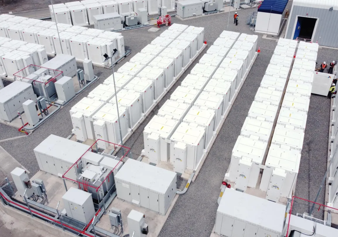 Aerial view of a large battery storage facility with rows of white containers and electrical equipment.