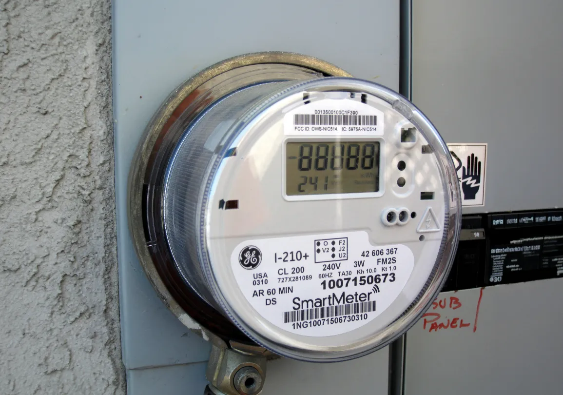 A General Electric I-210+ digital smart meter mounted on an electrical panel.