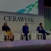 Five people sit on a panel stage at CERAWeek by S&P Global. They are seated in chairs with nameplates: Zhou, Ballentine, Smith, Manous, and Moreno. The backdrop features the CERAWeek logo and geometric designs. The panelists are engaged in discussion, with one speaking and others listening.