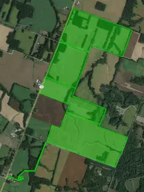 Aerial view of farmland with a highlighted area outlined in green, showing fields and roads in a rural landscape.