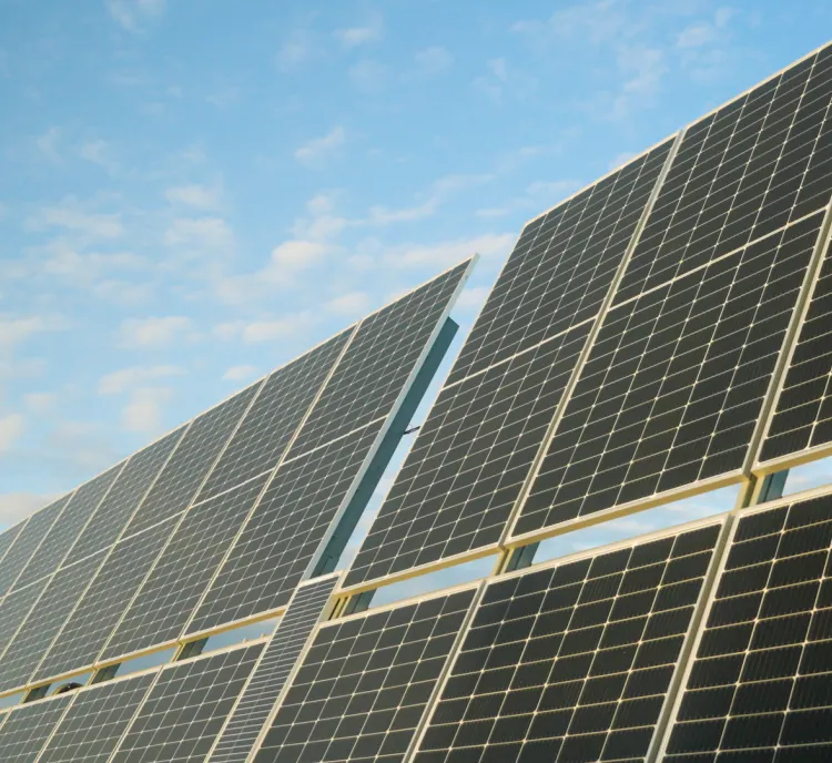 Close-up view of solar panels under a blue sky with scattered clouds.