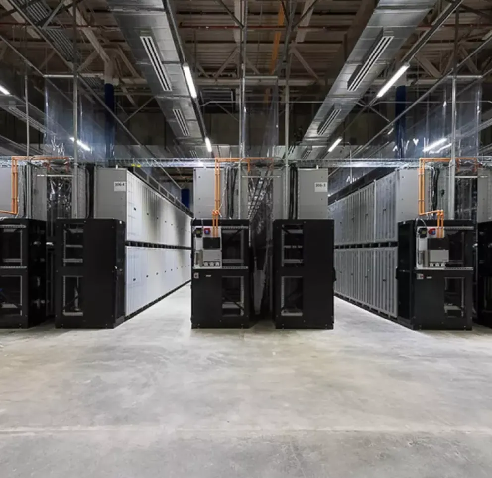 Interior view of a modern data center with rows of server racks and overhead cabling.