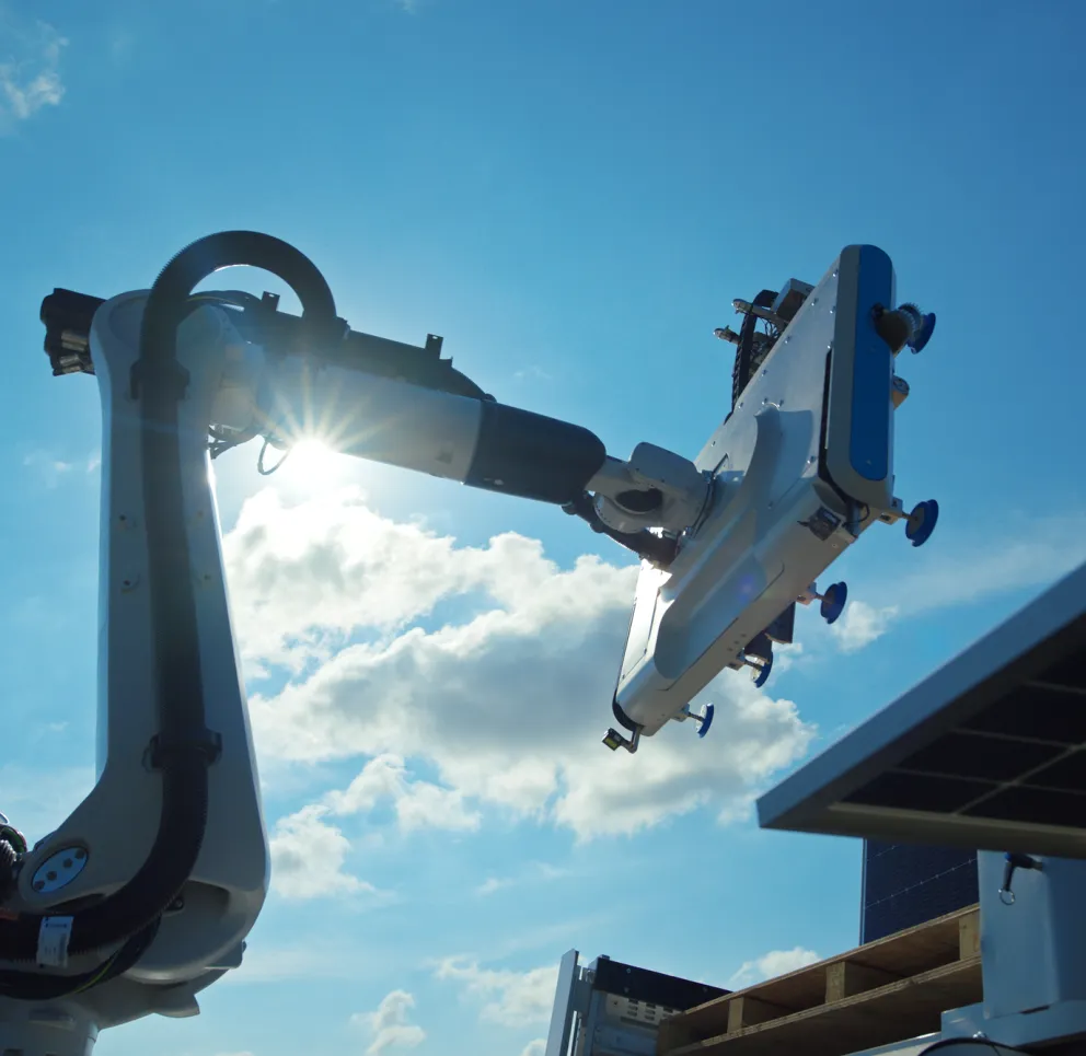 A robotic arm with a suction device operates under a bright blue sky with the sun shining through, highlighting its mechanical structure.