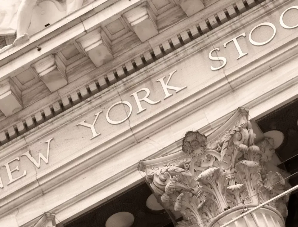 Sepia-toned close-up of the New York Stock Exchange building facade, featuring intricate architectural details and a Corinthian column.