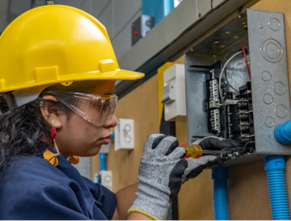 A person wearing a hard hat and goggles working on a machine  AI-generated content may be incorrect.