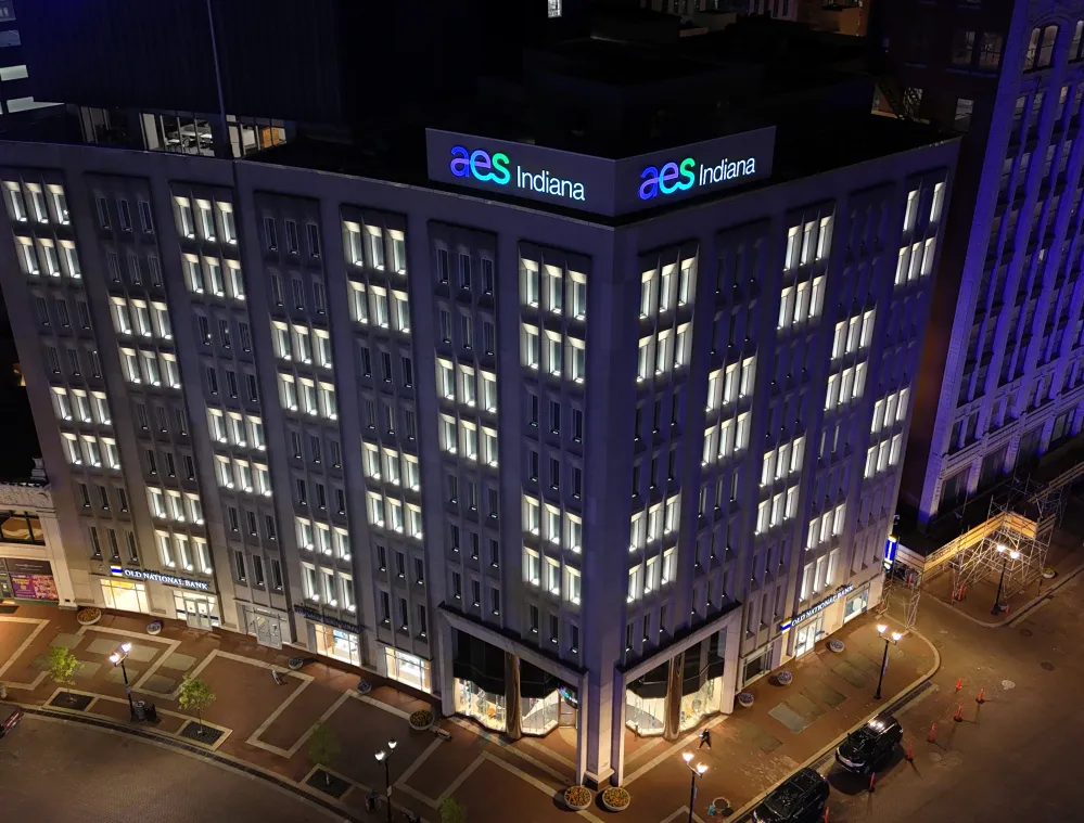 Aerial view of a lit-up AES Indiana office building at night.